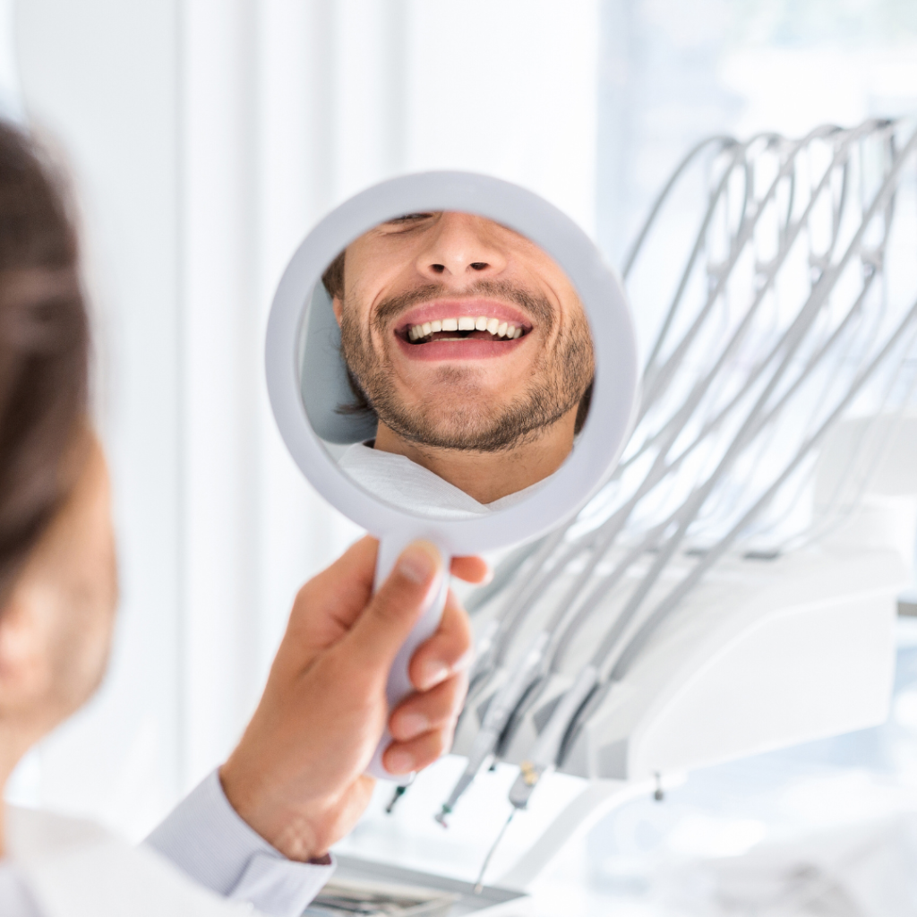 Dental fillings in Leicester at Smile Perfections dentist Leicester, showing a man smiling at his reflection in the mirror after receiving tooth restoration treatment.