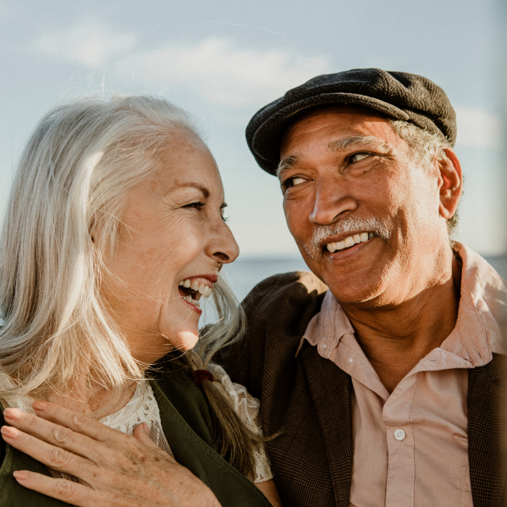 couple of older people smiling, looking at each other after getting dentures