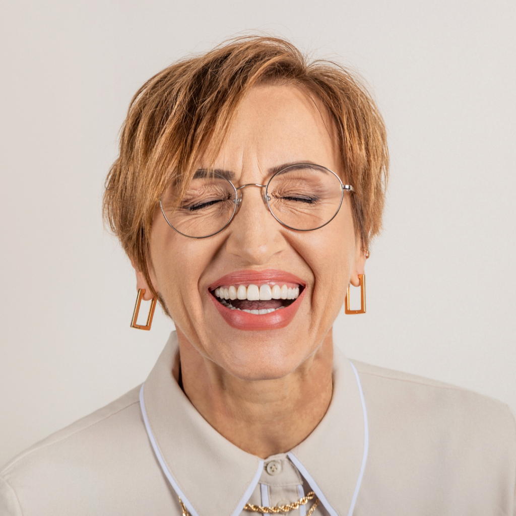 slightly older woman smiling with her eyes closed showing off her dentures without being noticed