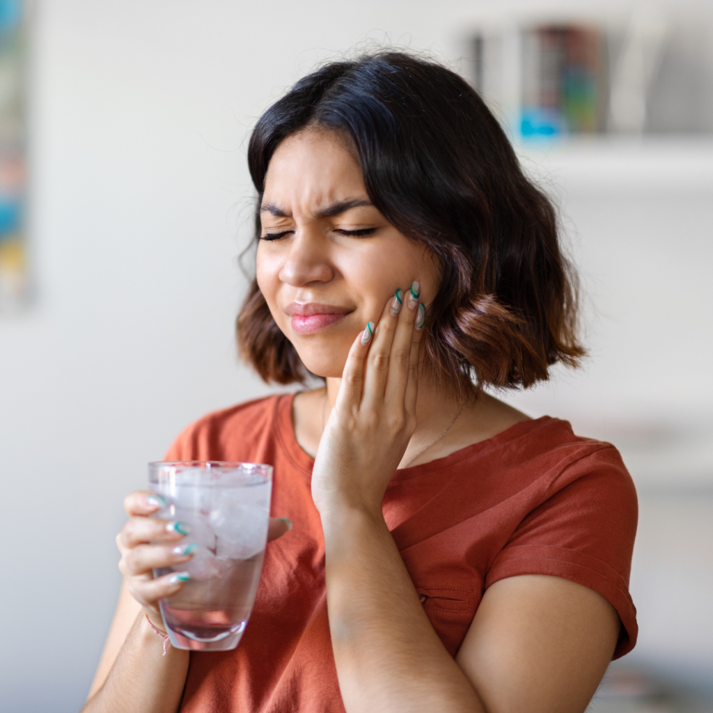 Dental filling treatment in Leicester at Smile Perfections dentist Leicester, featuring a girl holding her cheek after drinking water, possibly indicating sensitivity or discomfort.