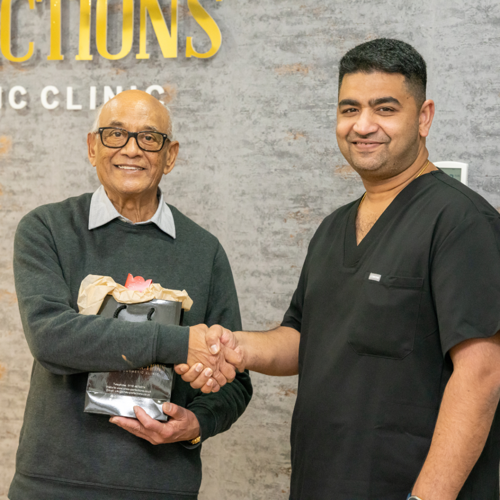 Dr Juttes and Mr Patel smiling together at Smile Perfections dentist Leicester, with Mr Patel holding a branded goodie bag, celebrating a positive dental experience.